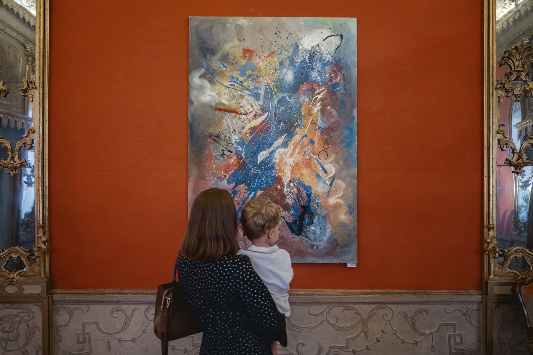 An adult and child looking at a work in the SOGLIE exhibition